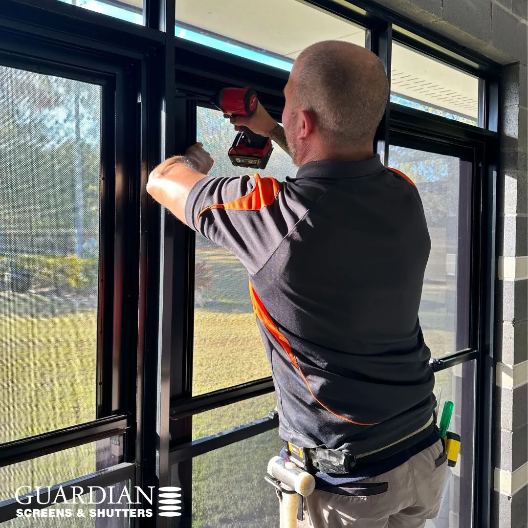 Clinton, a Guardian installer, fitting a window screen, drill in hand
