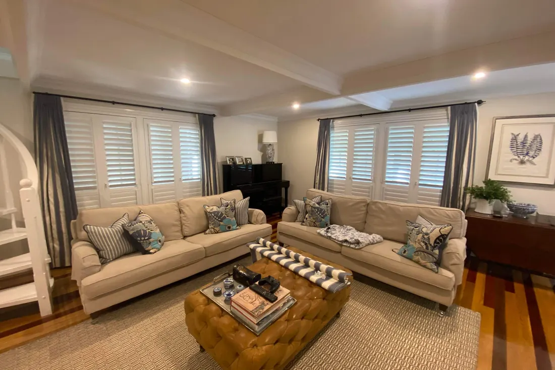 A living room with white Guardian shutters across both big windows
